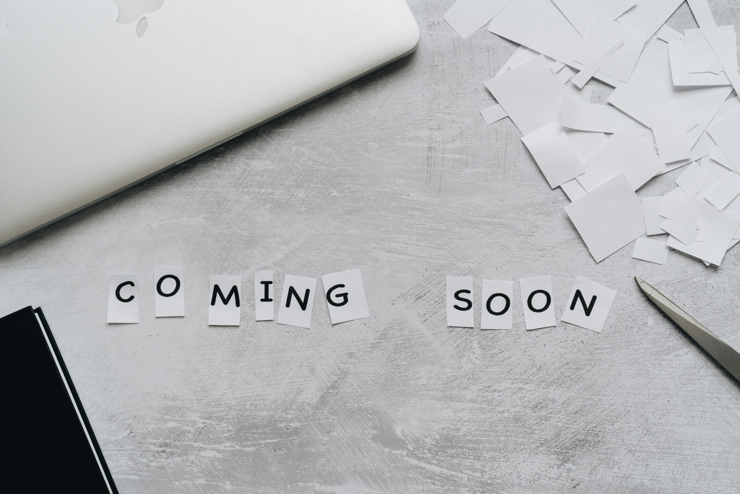 A creative arrangement with paper cutouts spelling 'Coming Soon' on a textured surface.